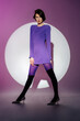 © Sergey Narevskih/Stocksy - Female model in purple dress standing spreading legs wide