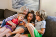 © ByLorena/Stocksy - Grandmother and grandchildren looking at phone
