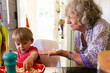 © ByLorena/Stocksy - Grandma and toddler making popcorn