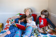 © ByLorena/Stocksy - Grandmother storytelling grandsons in bed