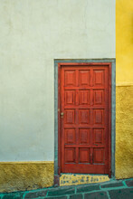 Colorful Red Door Against A Color-blocked Wall Of Green And Yellow