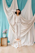 © Tania Cervian/Stocksy - Young woman covering face and standing against drapery