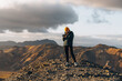 © Ivan Haidutski/Stocksy - young Woman backpacker Hiking Taking Photo on the top of Wild Mountain