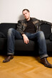© Designpics - young man sitting on a black sofa