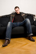 © Designpics - young man sitting on a black sofa