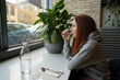 © Vradiy Art/Stocksy - Woman drinks water in cafe