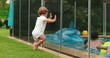 © Marco - Cute candid moment of baby leaning on pool fence wanting to interact with kids inside swimming pool