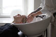 © Ivan Ozerov/Stocksy - Crop hairstylist washing hair of client in salon