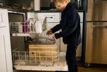 Little Boy Putting Dirty Dishes Into Dishwasher