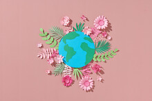 Globe With Paper Colorful Flowers And Leaves On A Pink Background.