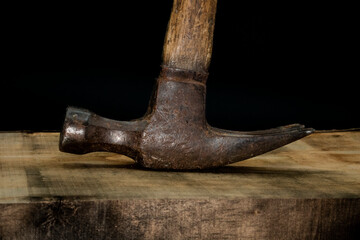 close up of hammer on wood with black background with reduced vibrance, grungy, old, antique, vintage