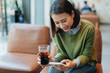 © Marc Tran/Stocksy - Asian woman holding coffee cup and play smart phone in coffee shop