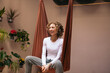 © Pedro Merino/Stocksy - Smiling woman sitting on a yoga cloth swing