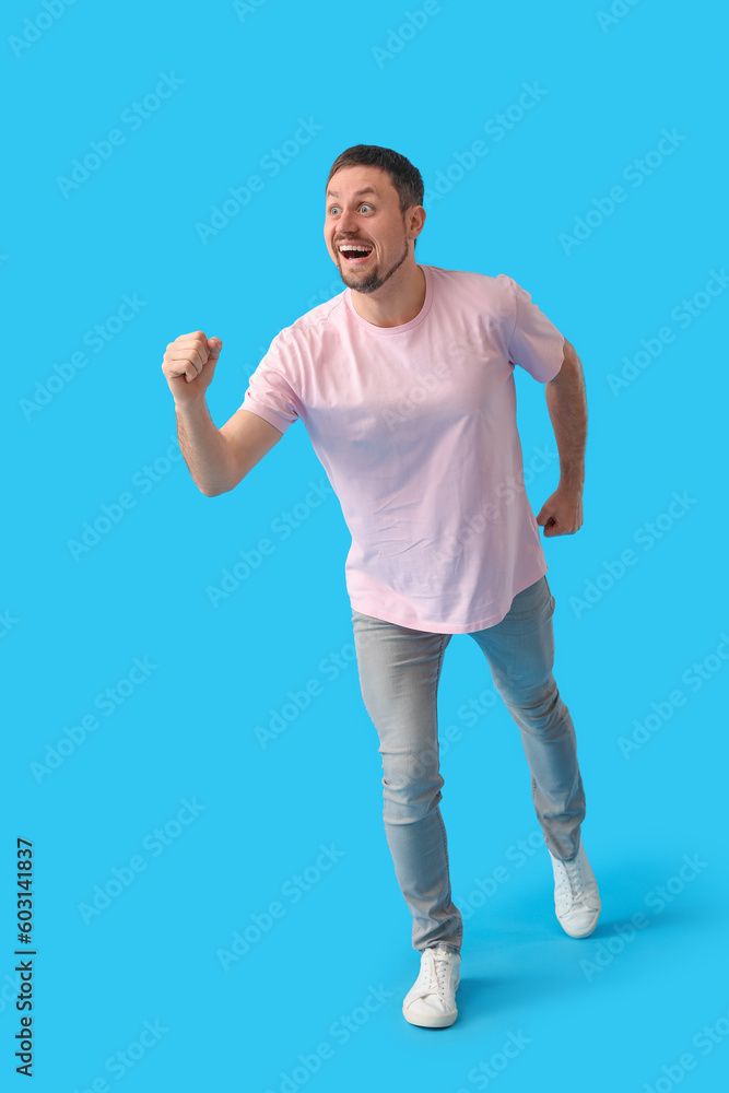 Handsome man in t-shirt running on blue background