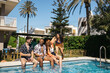 © Pedro Merino/Stocksy - Friends gathering by the pool in summer