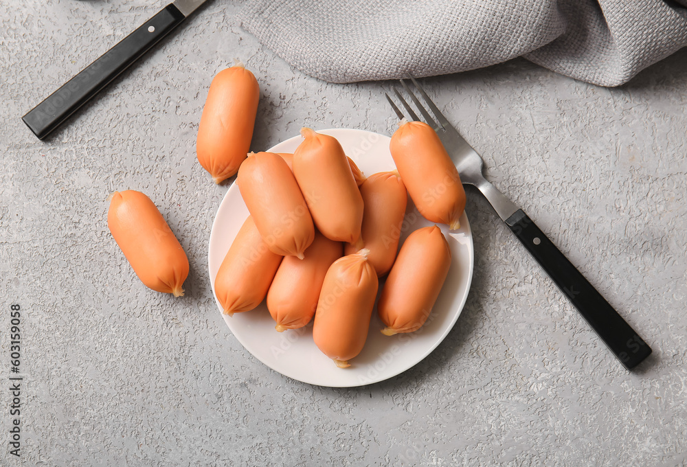 Plate of tasty boiled sausages on grey background