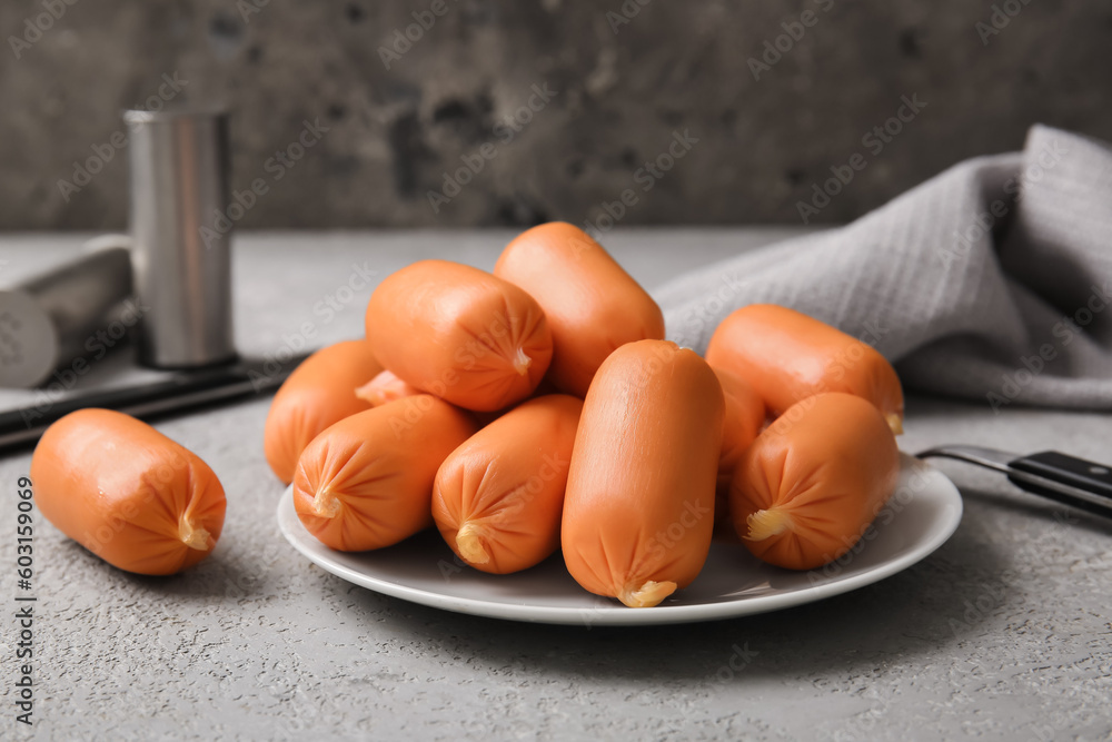 Plate of tasty boiled sausages on grey background