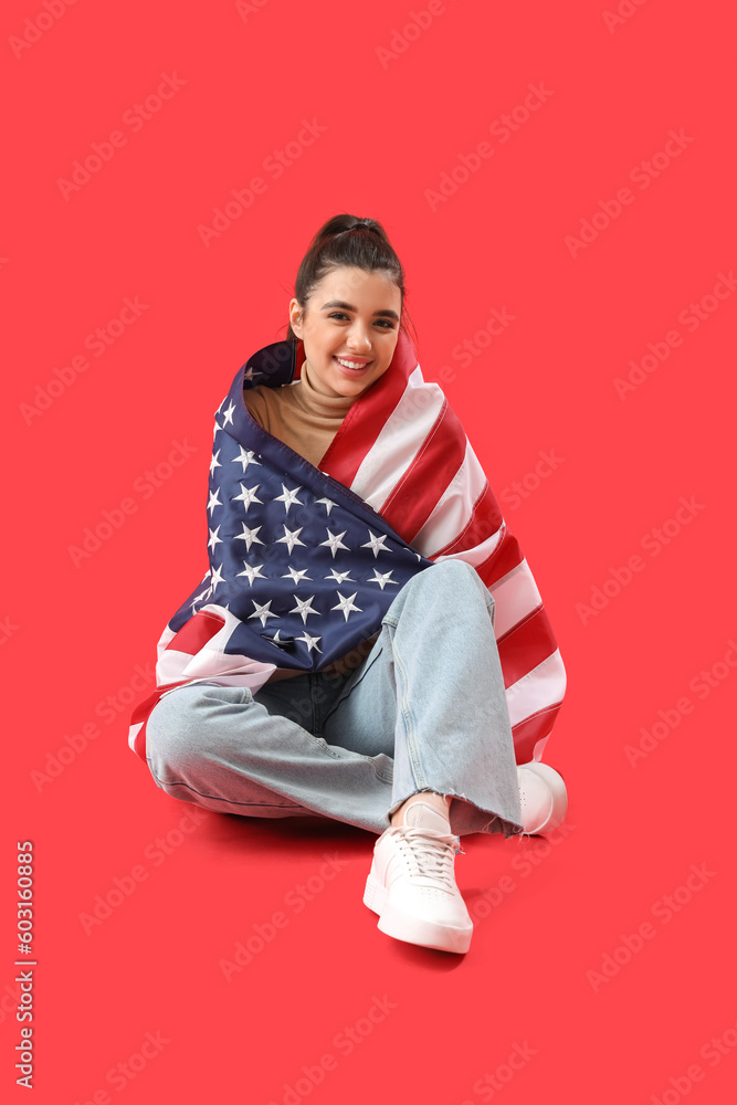 Young woman with USA flag sitting on red background