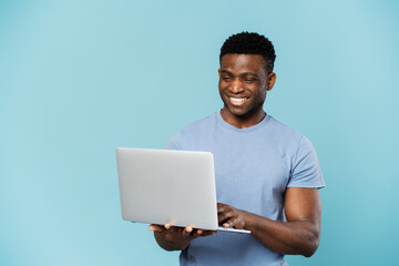 Smiling african american businessman using laptop isolated on blue background. Freelance concept