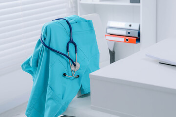 Wall Mural - Turquoise medical uniform and stethoscope hanging on chair in clinic