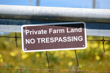 Private Farm Land No Trespassing Sign Posted On A Wire Fence. Close Up