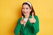 © sementsova321 - Flirting positive woman wearing green jacket posing isolated over yellow background showing finger guns to camera winking expressing happiness.