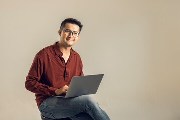 Simple young freelancer sitting working on laptop pc computer looking isolated on bright colored wall, studio photo background.