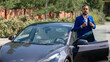 © Михаил Решетников - Caucasian bearded man in a blue suit gets out of a black electro car in the countryside in summer.