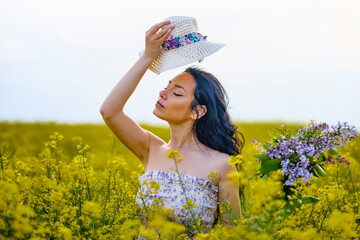 Wall Mural - portrait of a brunette woman in a rapeseed field in spring