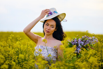 portrait of a brunette woman in a rapeseed field in spring