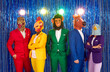Group of people in animal head masks standing shiny background. Male and female friends wearing colorful party suits and monkey, chicken, horse, dinosaur masks having fun at in disco club