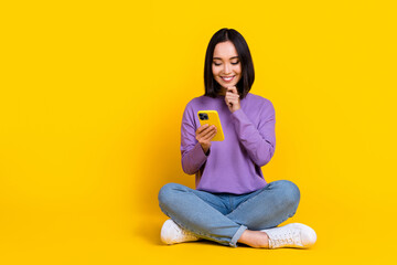 Wall Mural - Photo of shiny thoughtful woman wear violet shirt arm hand chin reading modern gadget empty space isolated yellow color background