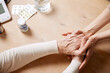 © master1305 - Close-up image of doctor's hand holding senior female patient hands, giving support and hope. Table with pills and meds. Concept of medical care, medicine, illness, health care, profession