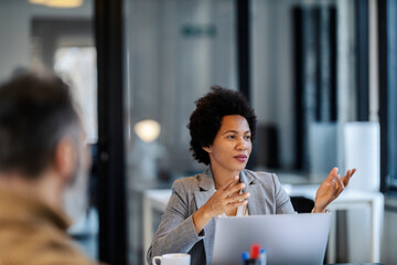 Wall Mural - A multicultural manager is sitting in a boardroom with her team of experts and explaining project.