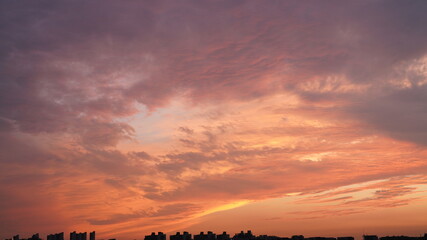 The beautiful sunset view with the buildings' silhouette and orange color sky as background in the city