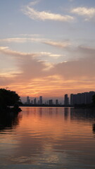 Wall Mural - the beautiful sunset view with the buildings' silhouette and orange color sky mirrored in the peacef