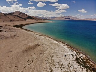 Road trip on famous Pamir Highway: lake Karakul, Karakul village, border with Afganistan, snowy pamir mountains, traditional houses, drone footage