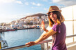 © unai - A female tourist from the Ferry and the city of Los Cristianos in the background on the island of Tenerife. Ferry coming from La Gomera, Canary Islands