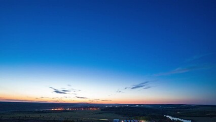 Wall Mural - Time-lapse sunrise over beautiful lake. Water surface in fast motion. Warm sky with rolling clouds. Trees silhouette woodland on horizon. Early morning shot in timelapse. Bright sun rises over skyline