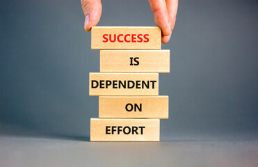 Success and effort symbol. Concept words Success is dependent on effort on wooden block. Beautiful grey table grey background. Businessman hand. Business success and effort concept. Copy space.