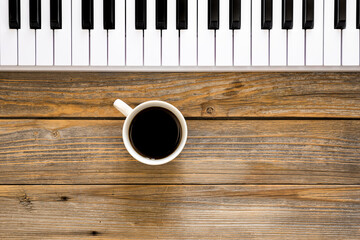 Wall Mural - Piano keys and a cup of coffee on a wooden background, top view. Musical background, the concept of musical creativity, copy space.