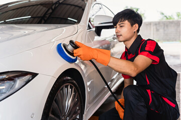 Wall Mural - Young Asian male employees using polishing tools to remove streaks on a white car, car wash workers polishing car paint.