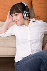 Wall Mural - attractive brunette woman with headphones sitting on floor