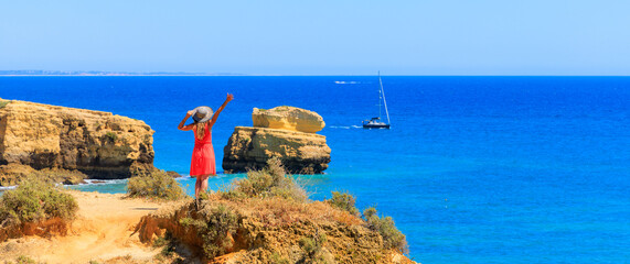 Wall Mural - woman with red dress enjoying panoramic view of atlantic ocean- Algarve in Portugal