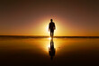 © Veronika Z. Gaudet - Silhouette of a young man walking on the beach backlit by setting sun and his reflection in the wet sand