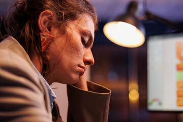 Tired businesswoman sleeping at desk table in startup office, working late at night at marketing strategy. Overworked business owner checking financial graphs report, falling asleep at job