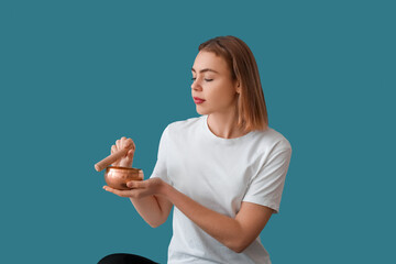 Wall Mural - Young woman with Tibetan singing bowl on color background