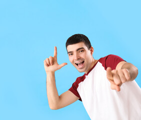 Canvas Print - Young man showing loser gesture on blue background