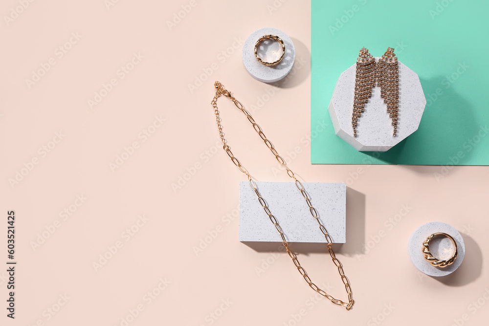 Decorative podiums with golden jewellery on color background