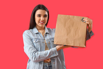 Canvas Print - Young woman with paper bag of sushi on red background